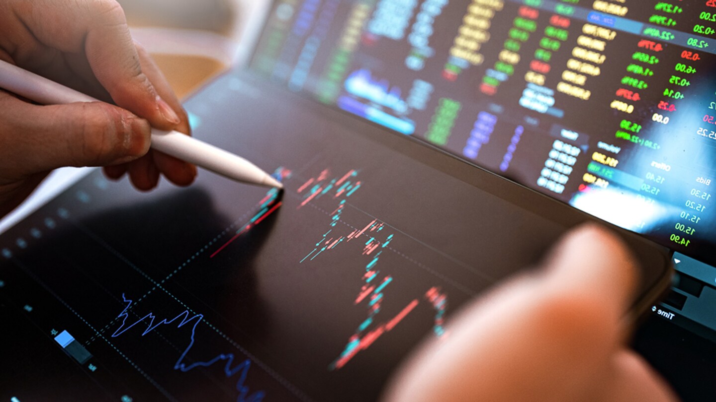 image of a hand holding an ipad with the focus being on a graph on the ipad and a hand holding an pencil to the screen