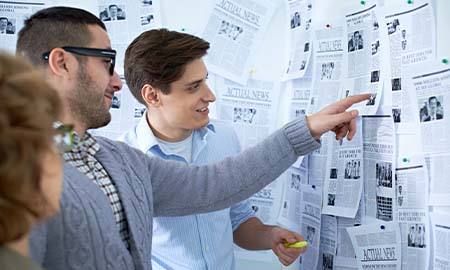 People looking at news paper on wall