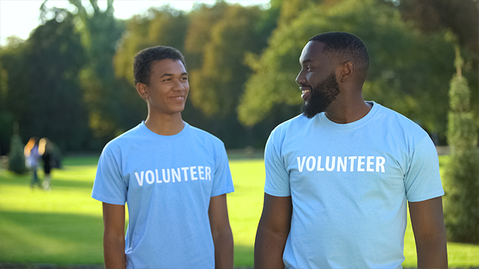 Two volunteers walking in a park.