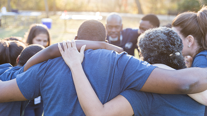 Group of volunteers hugged around in a circle.