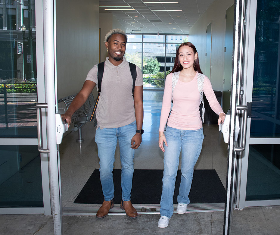 Two UHD students exiting the doors of a campus building