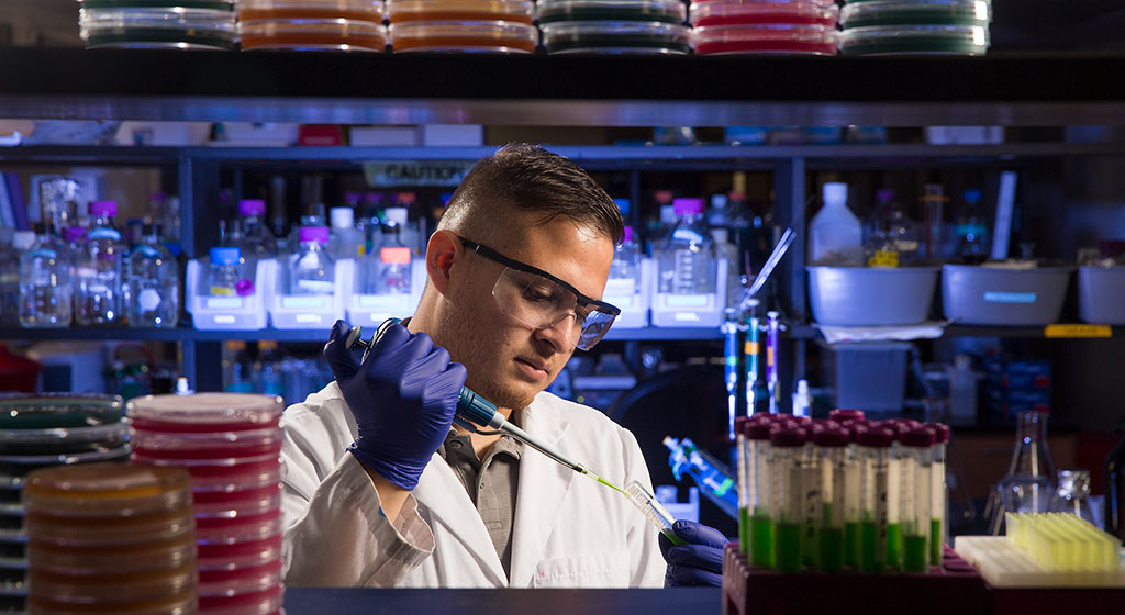 Man adding a solution to a test tube.