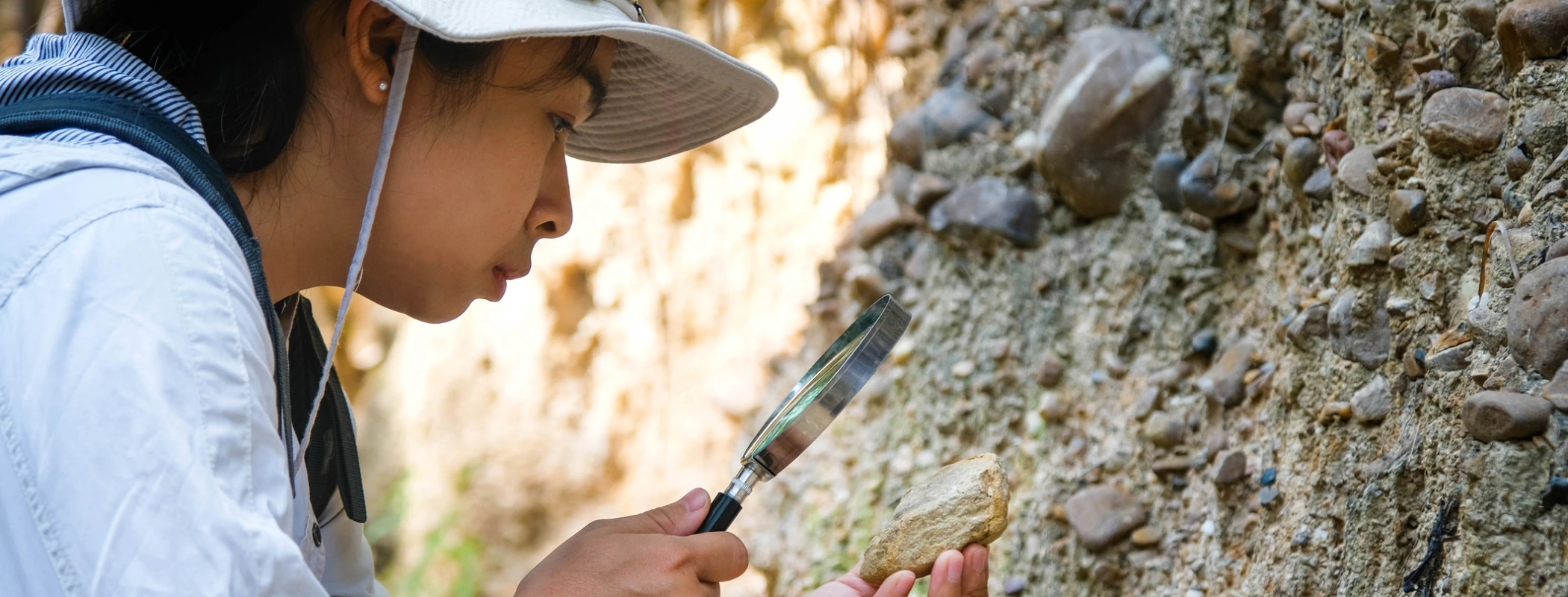 Female geologist using a magnifying glass to examine nature.