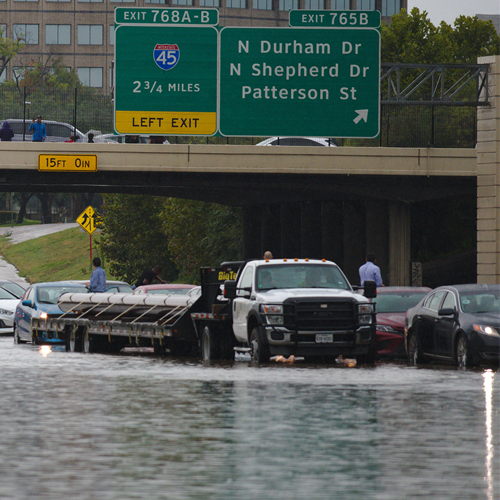 Cars attempt to drive through flood waters on I-10 in Houston