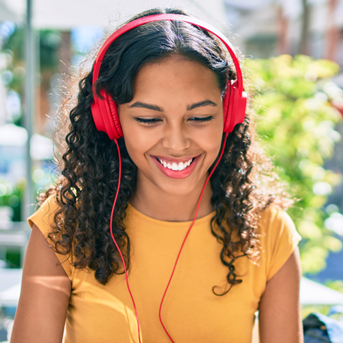 female student sitting outside and wearing headphones