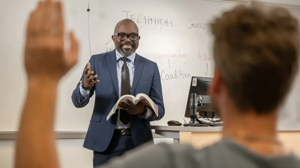 UHD faculty in a suit teaching in front of a classroom