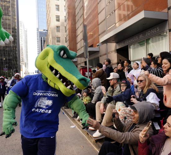 mascot edugator shakes hands with the crowd at the heb thanksgiving day parade