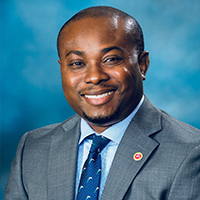 John Atasie, university of houston-downtown alum,  seasoned global supply management professional, wears a suit and smiles