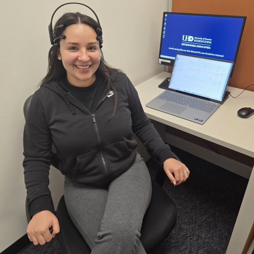Student researcher Alexandra Hernandez sits in a chair while wearing an EEG bands