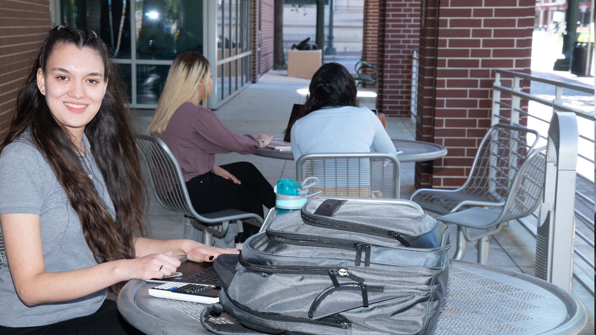 UHD female student sitting at a table outside of the CPS building