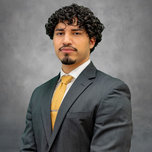 Denilson Fernandez smiles with a suit and tie