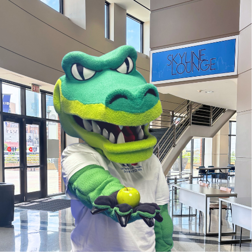 University of houston-downtown mascot ed-u-gator holds a green apple in the university's skyline lounge