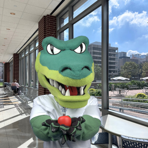 Ed-U-Gator holds an apple at the College of Public Service at the university of houston downtown
