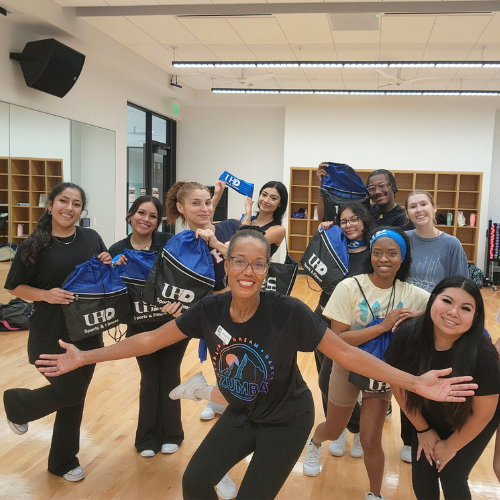 Cheerleaders on the University of Houston-Downtown squad smile with university bags at a Zumba class held at the wellness and success center 