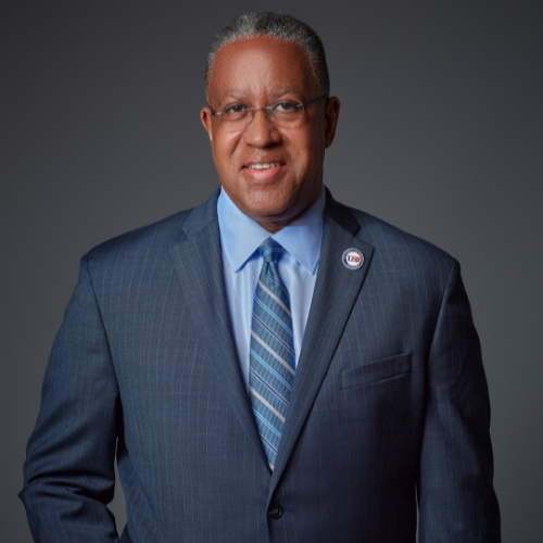 University of Houston-Downtown President Loren J Blanchard smiles while wearing a blue suit and tie