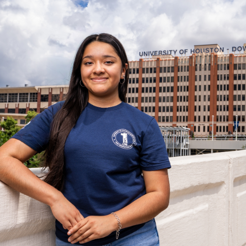 Criminal Justice sophomore Emily Raygoza wears a first generation t-shirt while standing on the Main Street bridge. The University of Houston-Downtown's One Main Building is behind the student. 